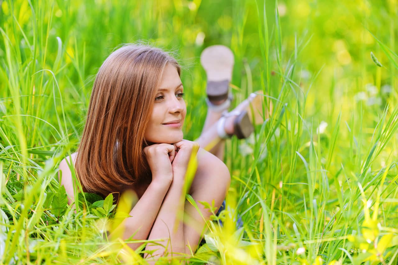 Eine glückliche Frau liegt im Sommer im Gras