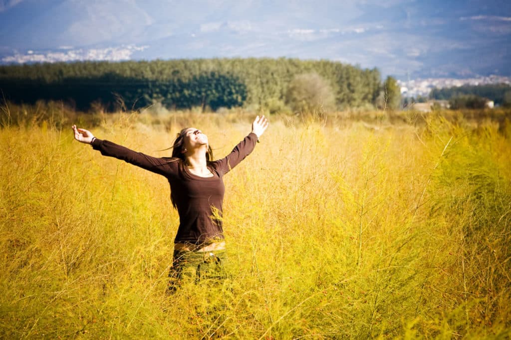 Eine freudige Frau im Weizenfeld mit hochgestreckten Armen