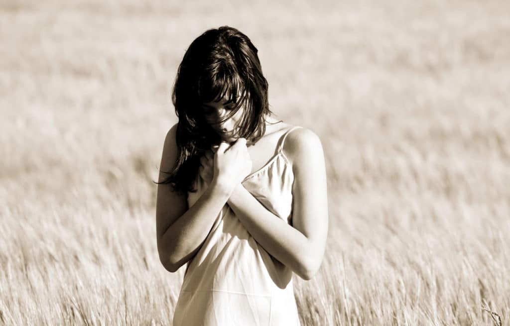 Eine Frau zeigt Emotionen und steht in einem Weizenfeld